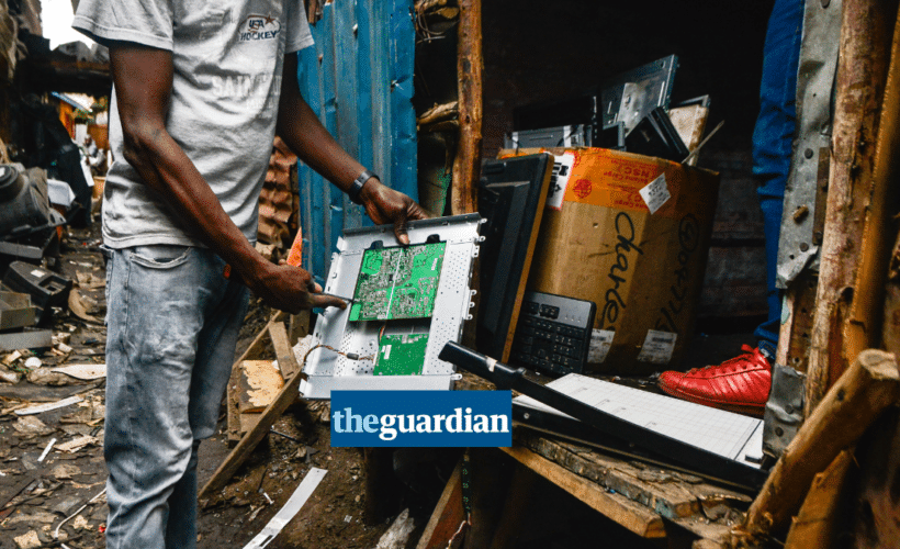a waste picker holding a piece of plastic e-waste, Guardian logo in the foreground